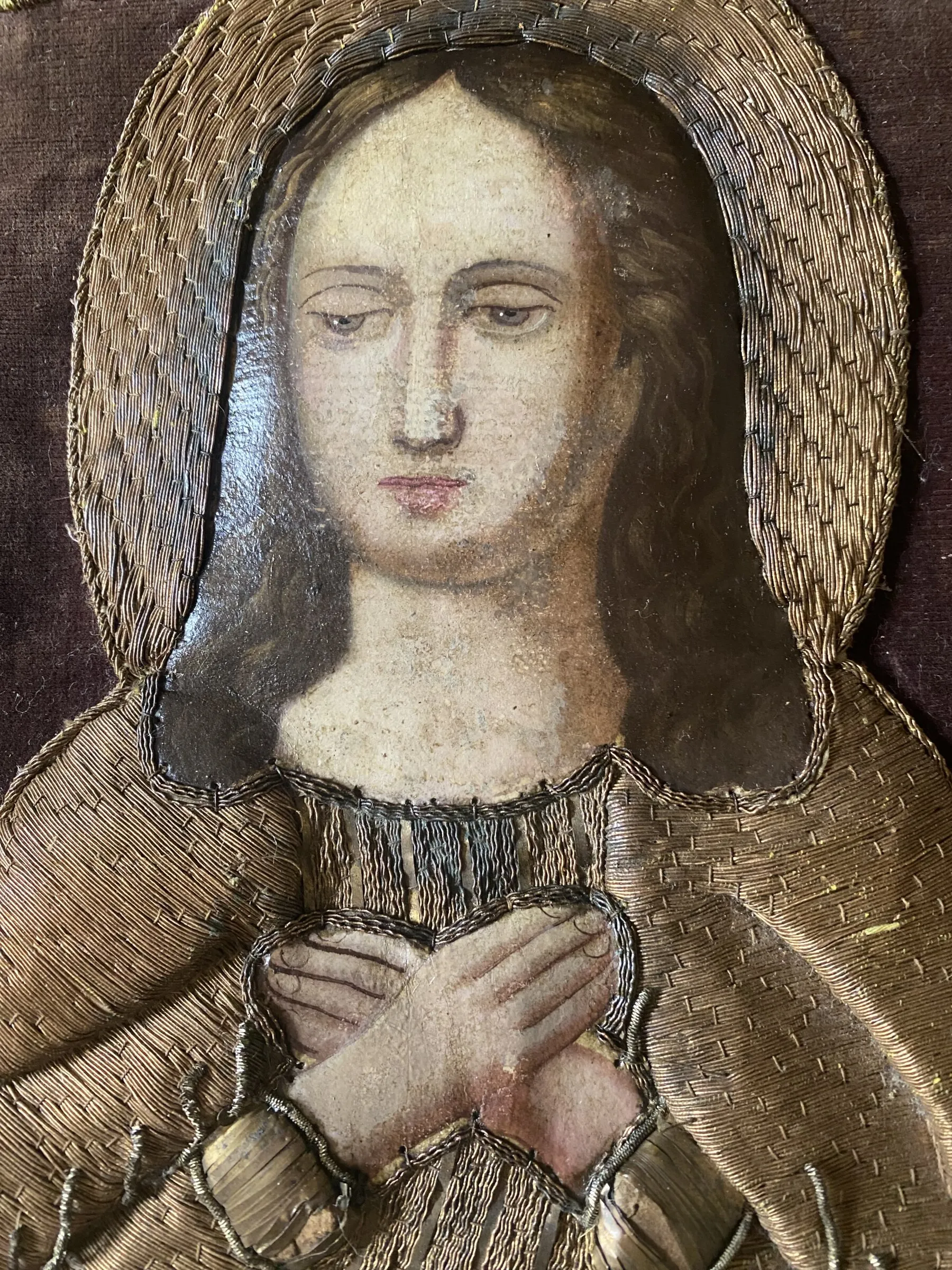 Detail eines Gesichts, gerahmt von Metallstickerei.