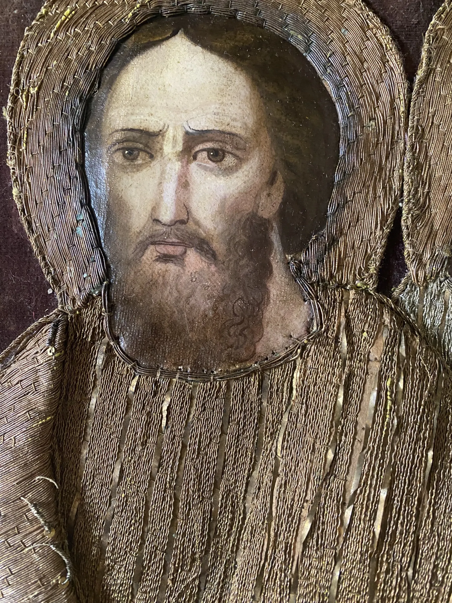 Detail of a male face framed by metal-thread embroidery.